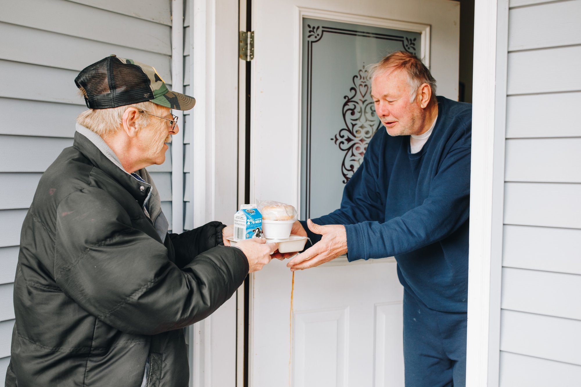 older man handing a meal to another older man